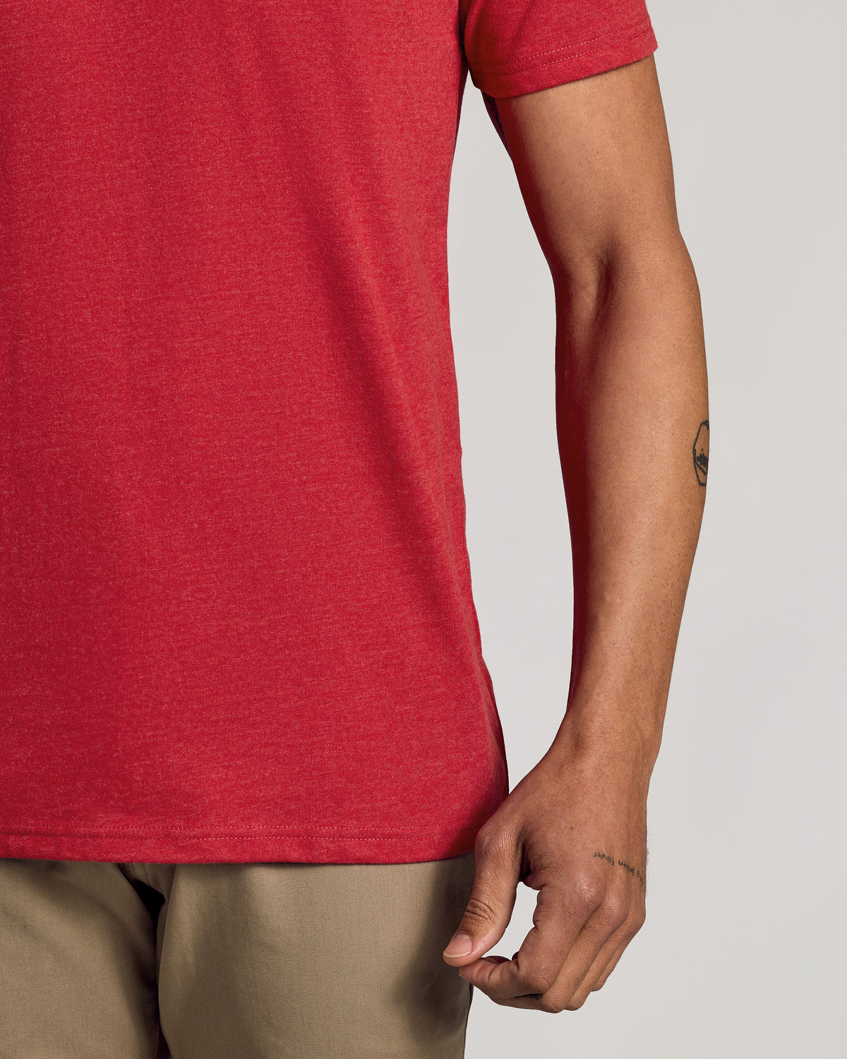 Dark Heather Lava Tee with tattoos visible on forearm and wrist.