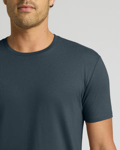 True ClassicA close-up of a man wearing a dark slate blue crew-neck t-shirt against a light gray background.