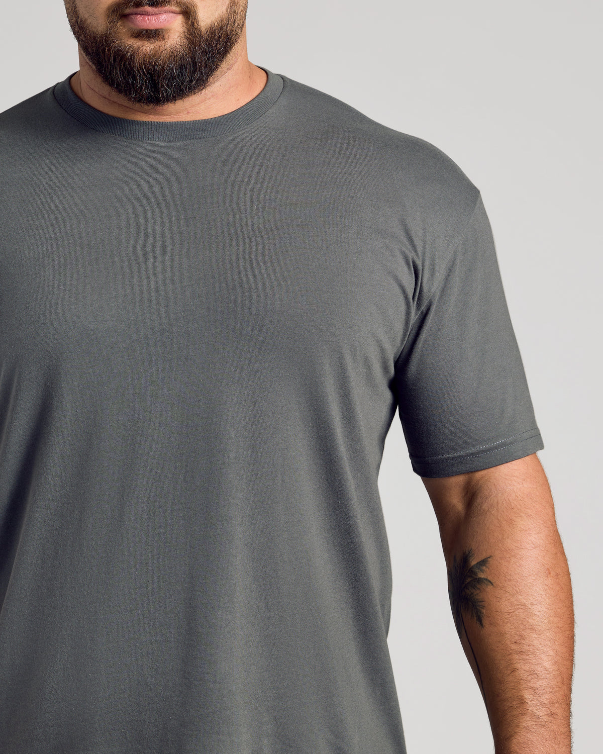 Man wearing Carbon Classic Crew Neck showcasing tattooed forearm.