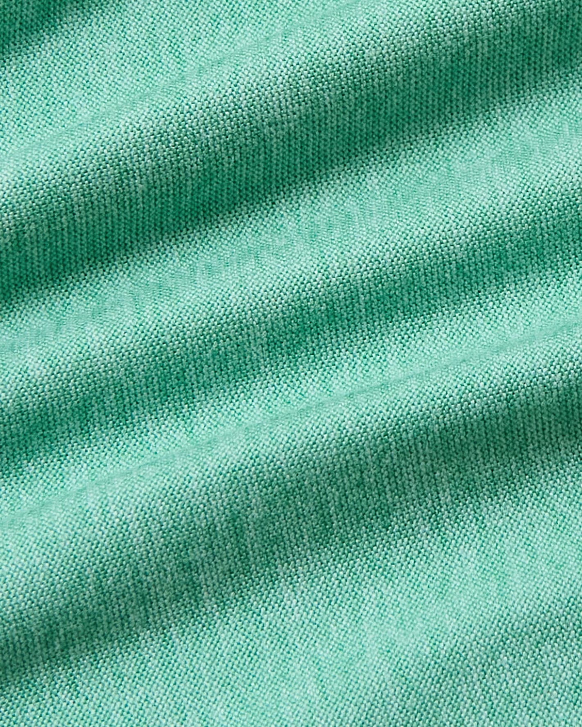 A close-up of mint green knit fabric with soft diagonal folds and visible woven texture.