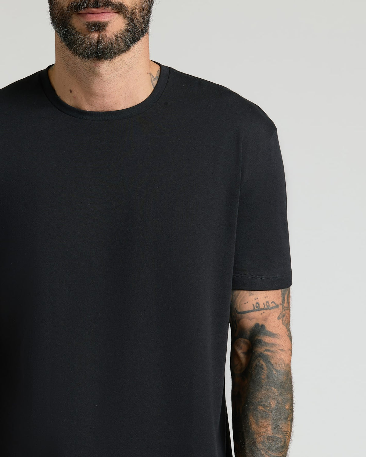 Close-up of a man wearing an all-black crew neck t-shirt from the All Black Pima Cotton Blend Crew 7-Pack, showcasing a smooth, comfortable fabric ideal for men's basics.