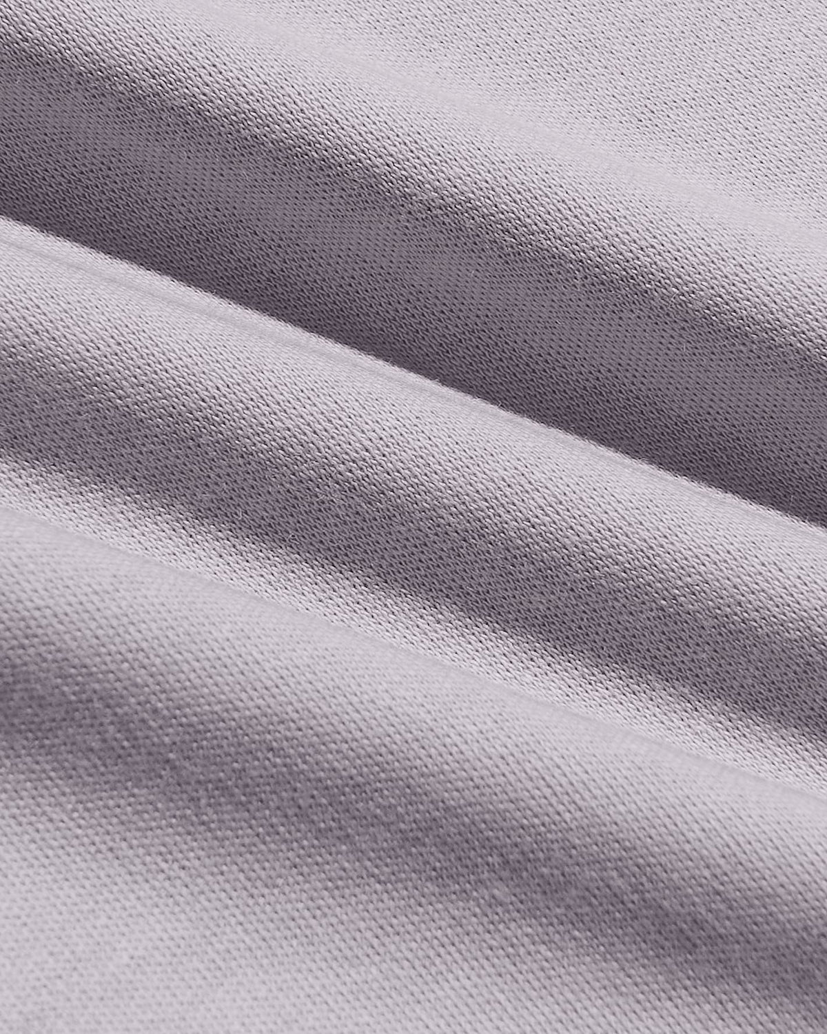 A close-up of draped light gray knit fabric with a fine ribbed texture and soft folds.