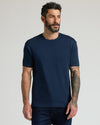 Man wearing a navy blue crew neck t-shirt from the Pima Cotton Blend Crew 4-Pack, paired with dark jeans, standing against a neutral background.