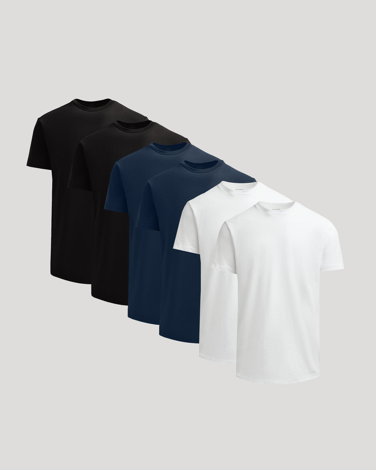 Two each of black, navy, and white True Classic Men's Heavyweight Curved Hem Crew – Premium Heavyweight Cotton Blend, Modern Athletic Fit, Structured Everyday T-Shirt displayed on a plain gray background.