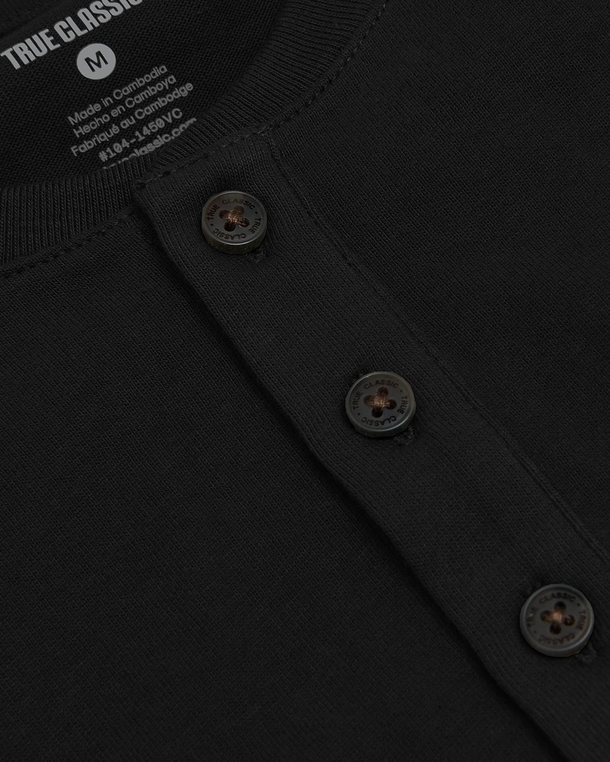 Close-up of a black heavyweight henley shirt showing button details and ribbed neckline, part of the All Black Heavyweight Curved Hem Henley 3-Pack men's basics by True Classic.