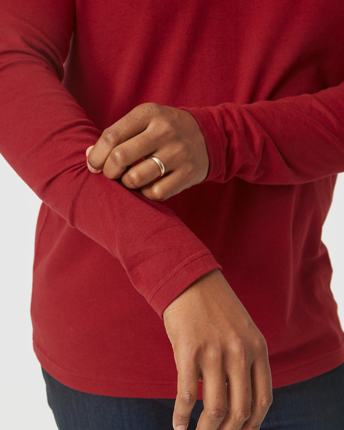 Close-up of a person adjusting the sleeve of a Crimson Long Sleeve Crew Neck, showcasing the soft fabric and casual fit of this men's basics shirt.
