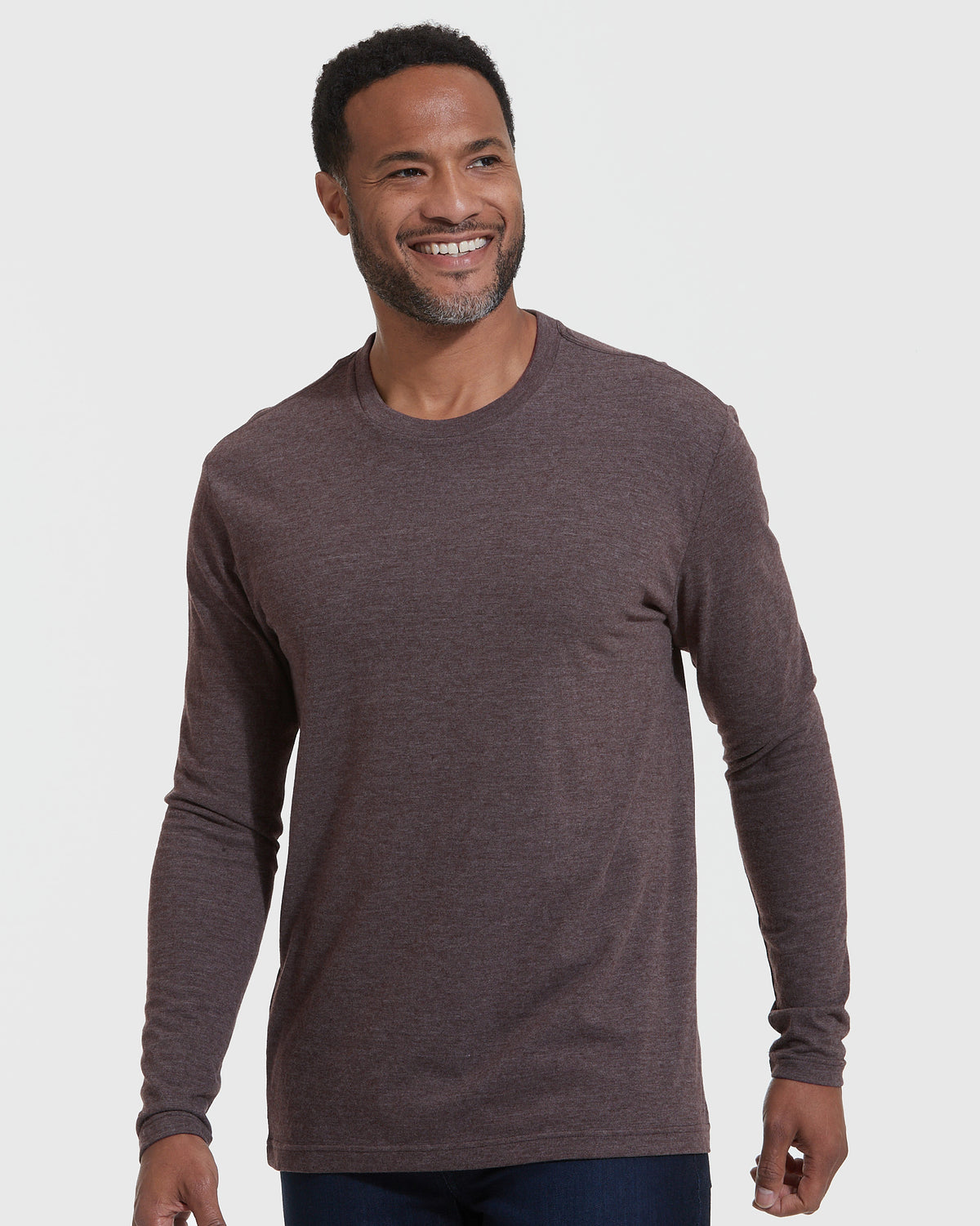 Man wearing Heather Dark Oak Classic Long Sleeve Crew Neck, smiling slightly off-camera.