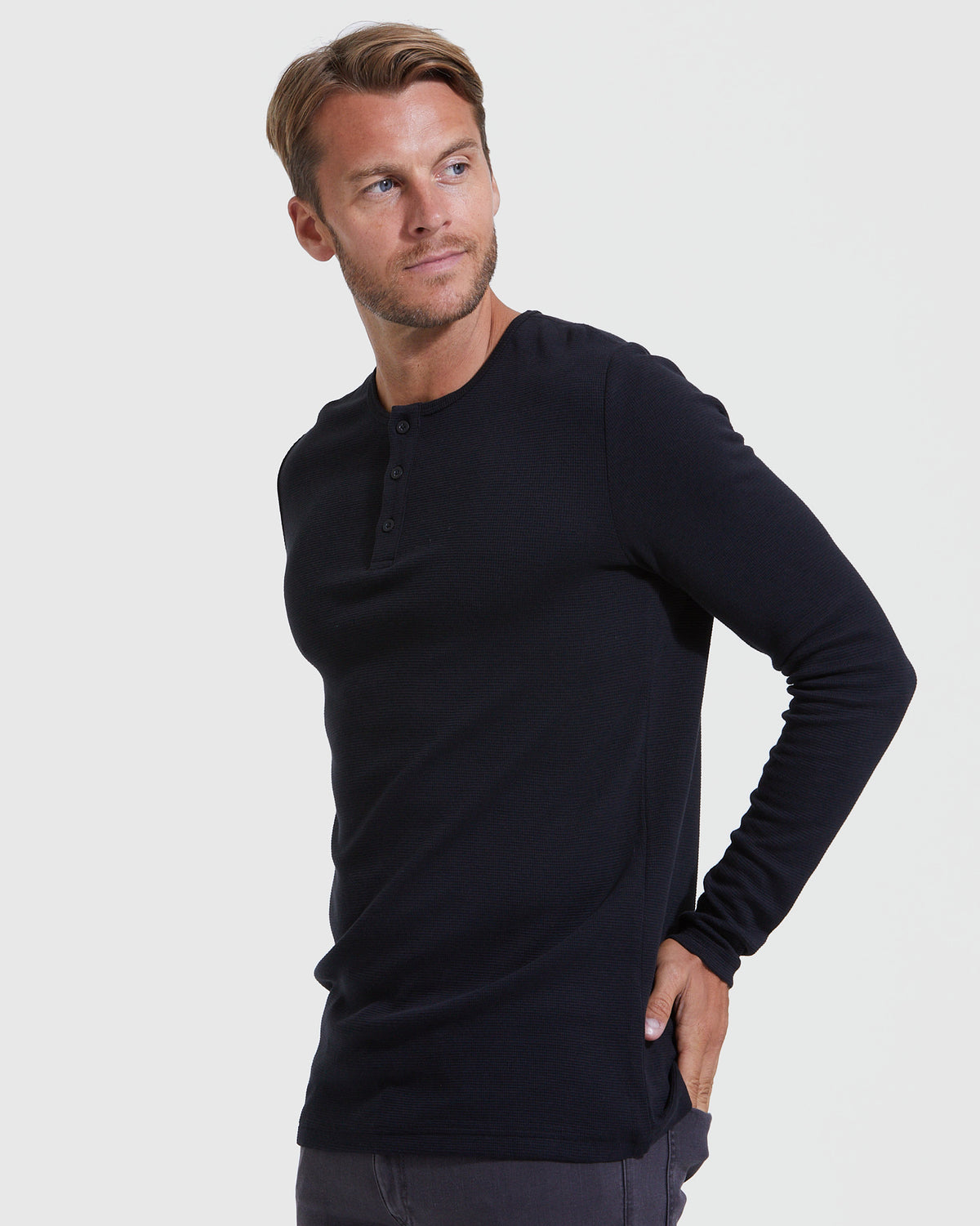 Man wearing a fitted black long sleeve Henley shirt with button detail, styled casually, showcasing the Black Waffle Long Sleeve Henley 3-Pack men's basics.