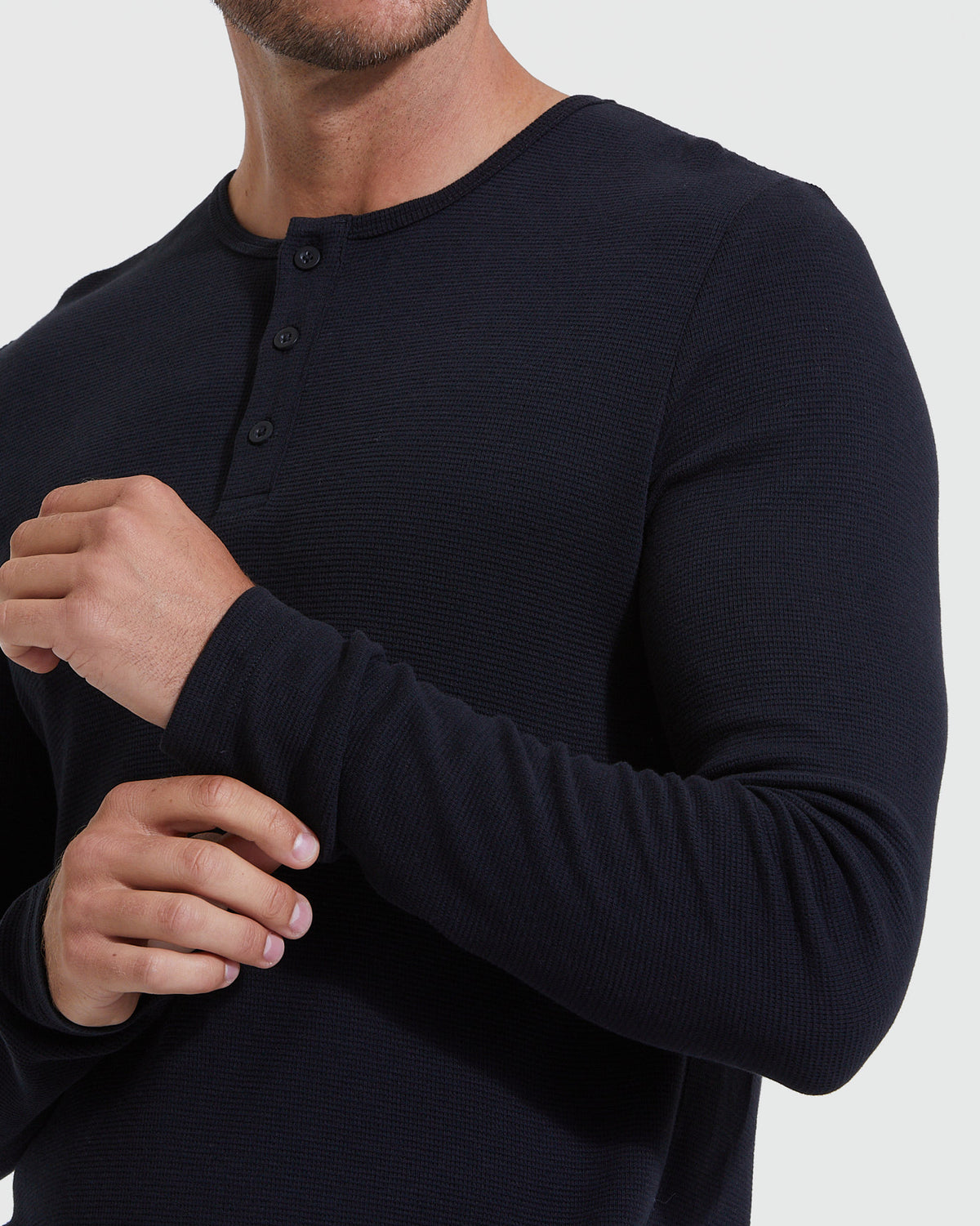 Man adjusting sleeve of Black Waffle Long Sleeve Henley.