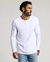 Man wearing a white long sleeve henley shirt paired with light blue jeans, showcasing The Standard Waffle Long Sleeve Henley 3-Pack as a comfortable men's basics essential.