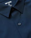 Close-up of a navy blue Navy Performance Long Sleeve Dress Shirt highlighting its smooth fabric, button details, and classic collar design from True Classic’s men's basics collection.