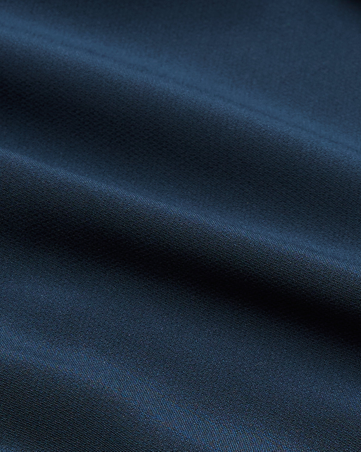 Close-up view of smooth navy fabric texture used in the Navy Performance Long Sleeve Dress Shirt, highlighting its refined weave and rich color for men's basics.