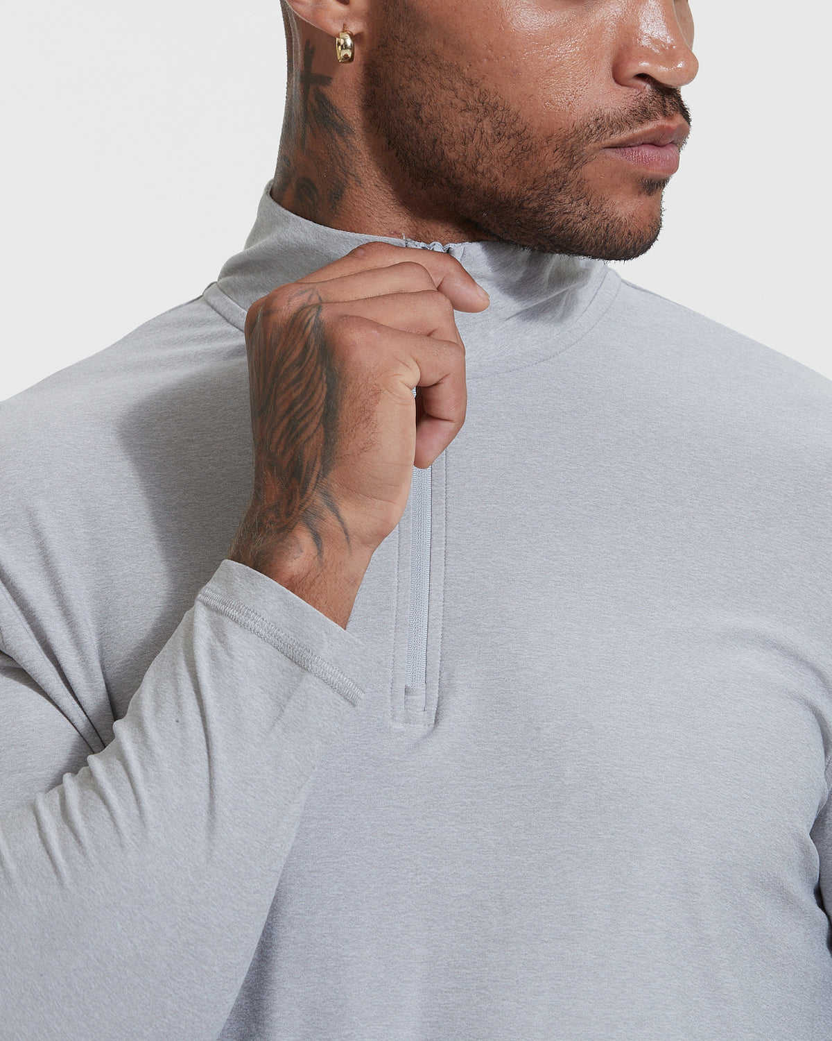 Man zipping Light Heather Gray Active Quarter Zip Shirt, showcasing tattoos.