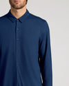 Man wearing a blue button-up shirt against a light gray background