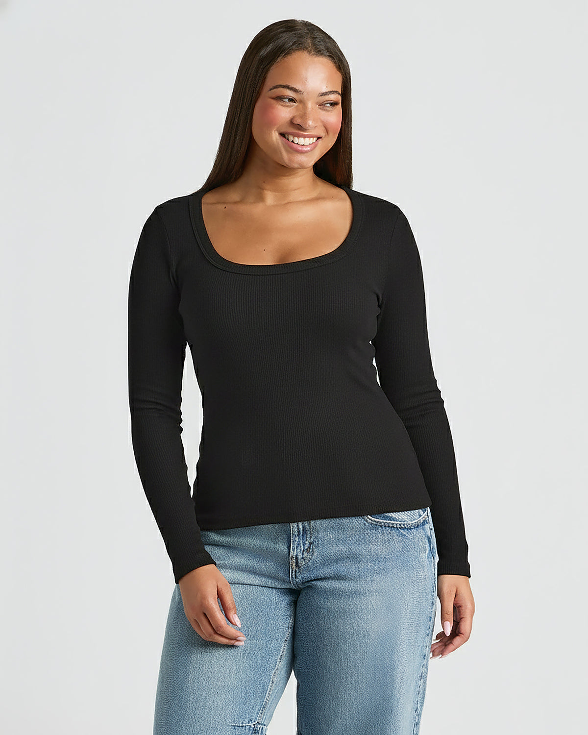 Woman wearing a black long-sleeve top and blue jeans on a light gray . MODEL_INFO: Jade is 5'9", wearing a size Lbackground