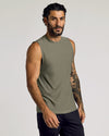 Man wearing a Heather Military Green Sleeveless Active Muscle Tee with a fit build and tattooed arm, posing confidently against a plain background in men's basics style.