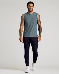True ClassicA muscular man wearing a heather navy Sleeveless Active Muscle Tee 3-Pack paired with black athletic pants and white sneakers, standing against a neutral background.