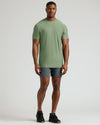Man wearing a sage green shirt styled as part of the Seasonal Tall Active Crew 3-Pack, paired with dark shorts and black sneakers, standing against a plain background.