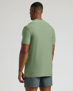 True ClassicMan wearing a sage green tall active crew neck shirt shown from the back, paired with gray athletic shorts, highlighting the fit and length in a minimal studio setting.