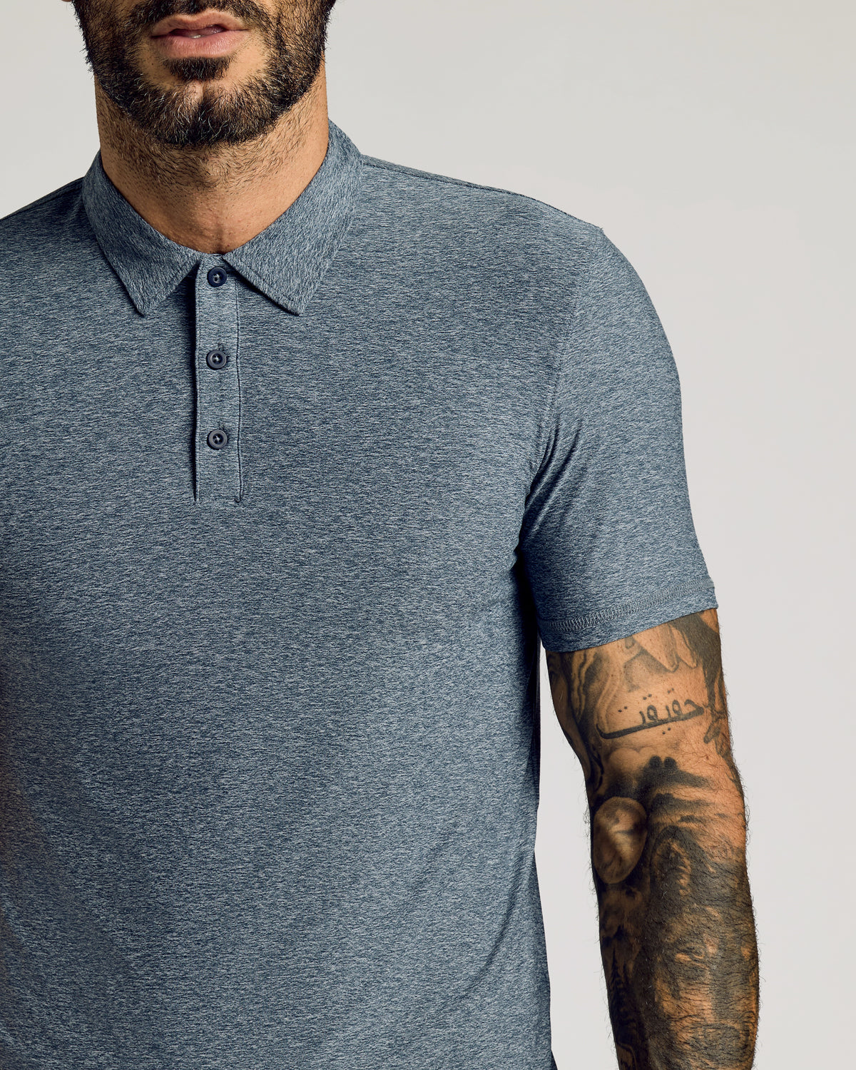 Heather Navy Short Sleeve Tall Active Polo on tattooed man's upper body.