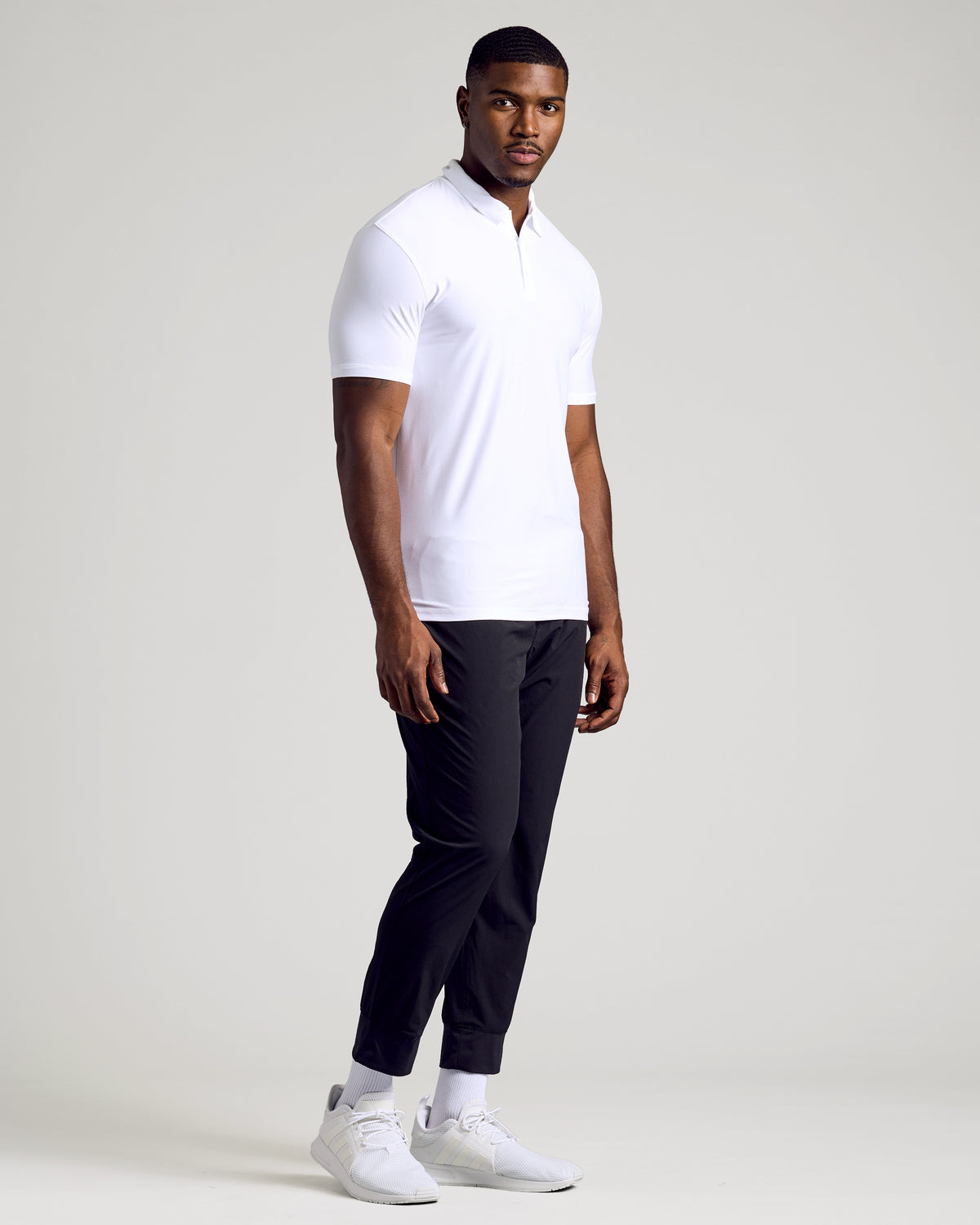 Man wearing White Short Sleeve Tall Active Polo and black joggers.