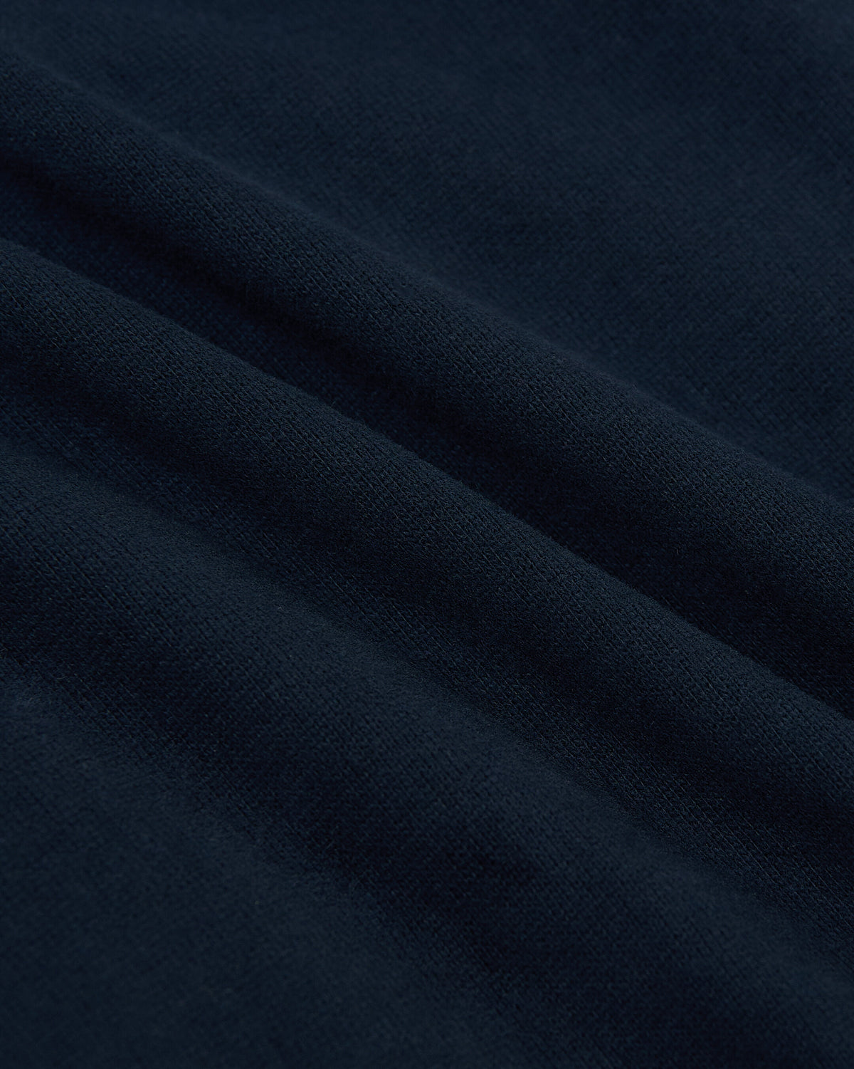 Close-up of soft navy fabric texture showcasing the material of the Navy Heavyweight Curved Hem Crew, highlighting its quality and deep blue color.