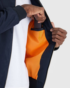 True ClassicUnzipping Navy Bomber Jacket to slip phone into inner chest pocket.