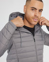 Man adjusting hood of Gunmetal Hooded Puffer Jacket, showcasing zipper details.