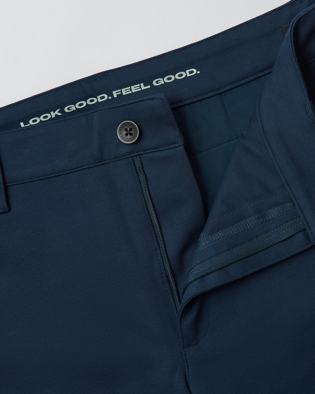 Navy Slim Comfort Knit Chino Pant with undone button and visible slogan.
