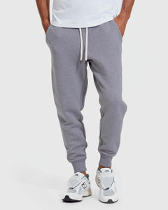 True ClassicFront view of a person wearing Heather Gray Fleece French Terry Joggers with a white drawstring, paired with white athletic sneakers, showcasing a casual men's basics style.