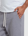 Man wearing Heather Gray Fleece French Terry Joggers with hand in pocket, showing soft fabric texture and white drawstrings on waistband.