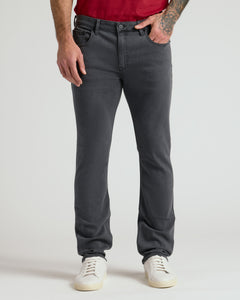 True ClassicCarbon Bomber Jacket & Comfort Stretch Jeans modeled with sneakers, tattoo visible.