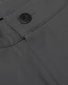 Close-up view of the waistband and button detail on men's Carbon Commuter Pants made from durable fabric in a dark charcoal color.