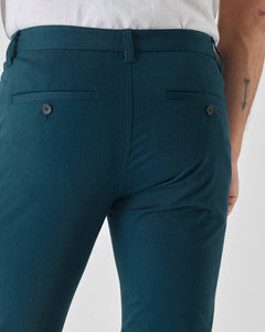 True ClassicCenturion Slim Twill Chino Pant, dark teal, welt pockets, arrow tattoo visible.