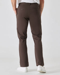 True ClassicDark Oak Straight Twill Chino Pant with white sneakers, hands in pockets.