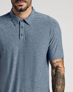 True ClassicMan wearing Heather Navy Active Short Sleeve Polo, tattooed forearm visible.