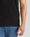 Person wearing a black t-shirt and blue jeans on a light gray background