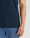 Person wearing a navy blue t-shirt and blue jeans on a light gray background