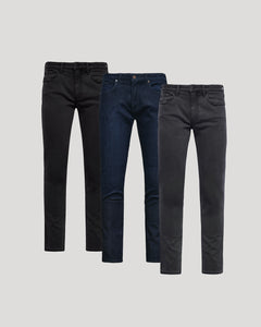 True ClassicThree pairs of men's Slim Comfort Stretch Jeans 3-Pack in black, dark blue, and charcoal gray, displayed against a neutral background.