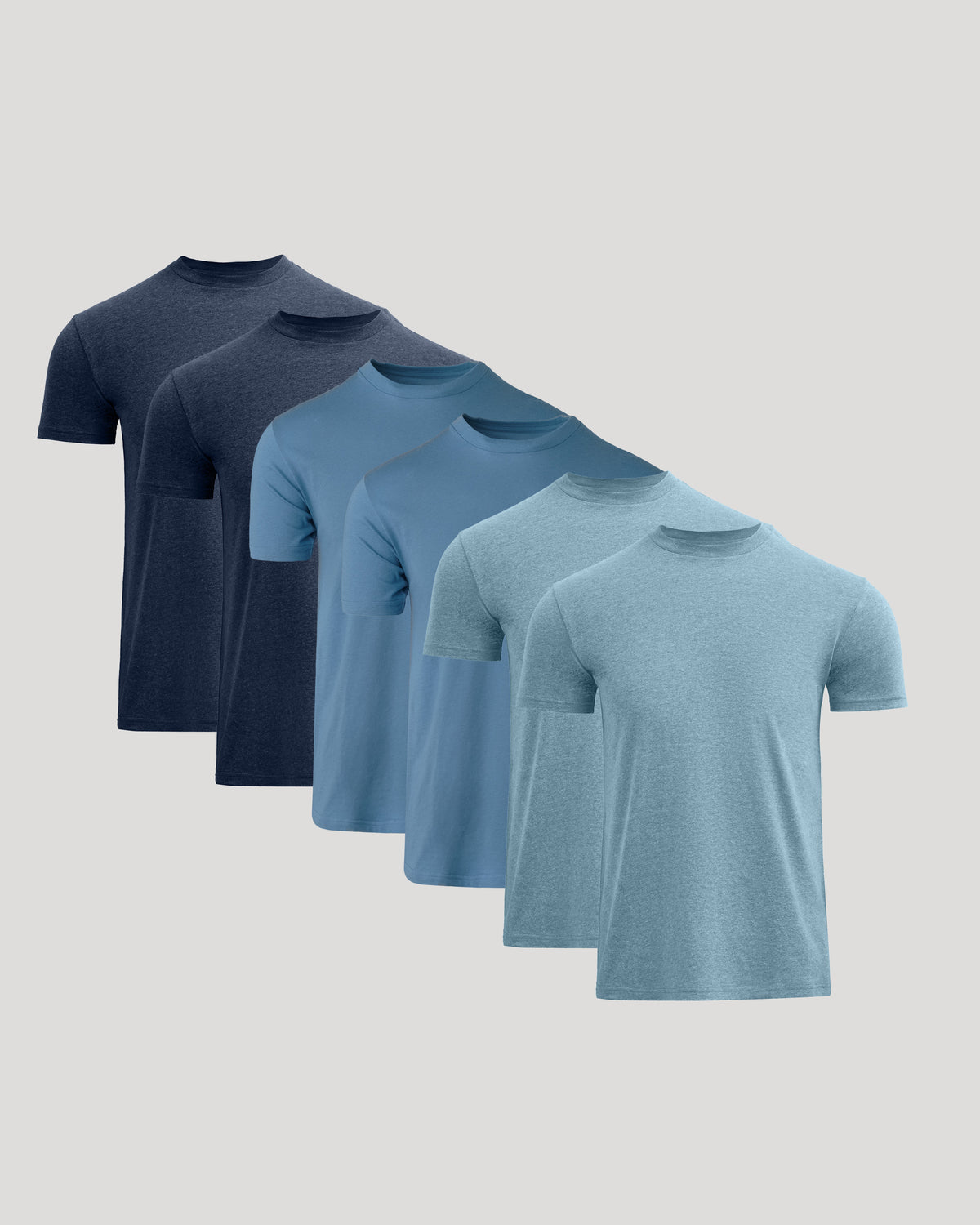Five short-sleeve crew-neck t-shirts in a gradient of dark navy to light heather blue, arranged in a staggered fan shape on a solid light gray background.