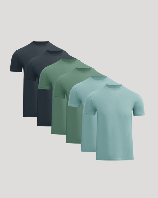 Five short-sleeve crew-neck t-shirts arranged in a staggered fan layout on a light gray background, shown in dark navy, charcoal, sage green, mint green, and light aqua.