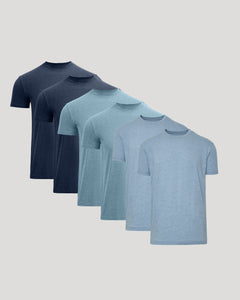 True ClassicFive short-sleeve crew-neck t-shirts in a gradient color selection, ranging from dark navy blue to light heather blue, arranged diagonally on a solid light gray background.