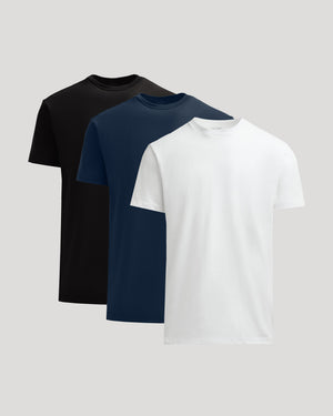 Three plain t-shirts in black, navy, and white on a light gray background
