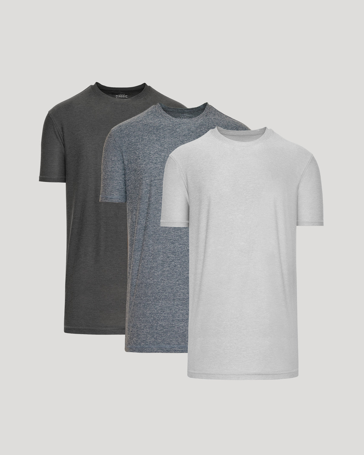 Three gray t-shirts in different shades on a light gray background