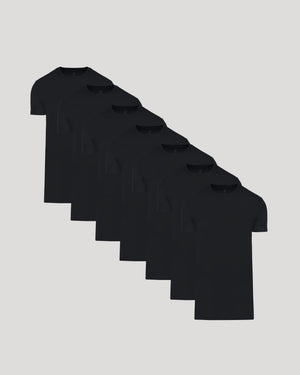 Seven black crew neck t-shirts arranged in a staggered row, showcasing the Tall Pima Cotton Blend Crew 7-Pack as essential men's basics.