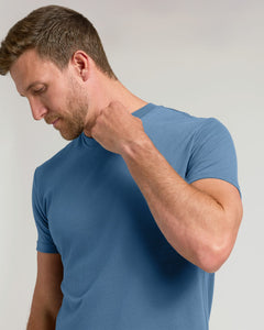 True ClassicA man wearing a blue short-sleeve crewneck t-shirt, shown from the chest up against a light gray studio background.