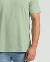 Person wearing a light green t-shirt and blue jeans on a plain background