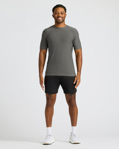 True ClassicA man modeling a dark gray short-sleeve athletic t-shirt and black athletic shorts against a light gray studio background.