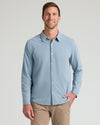 Man in Blue Stretch Oxford 2.0 shirt, tan pants, smiling.