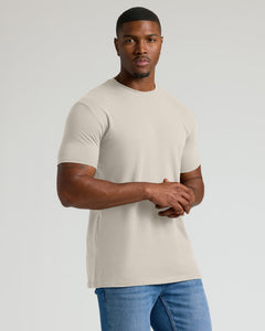 True ClassicMan wearing a beige t-shirt and blue jeans on a plain background